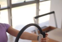 MZ세대부터 중장년층까지… 필라테스로 활기찬 일상 가꾸기 a woman sitting on the floor holding a steering wheel